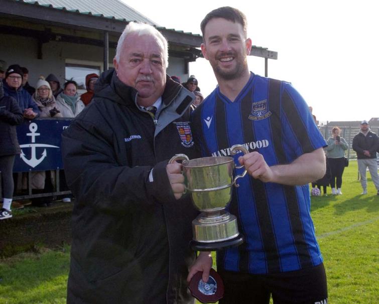 Hakin United skipper receives the Division 1 silverware from League chairperson Mackie Harts. Hakin United skipper receives the Division 1 silverware from League chairperson Mackie Harts.